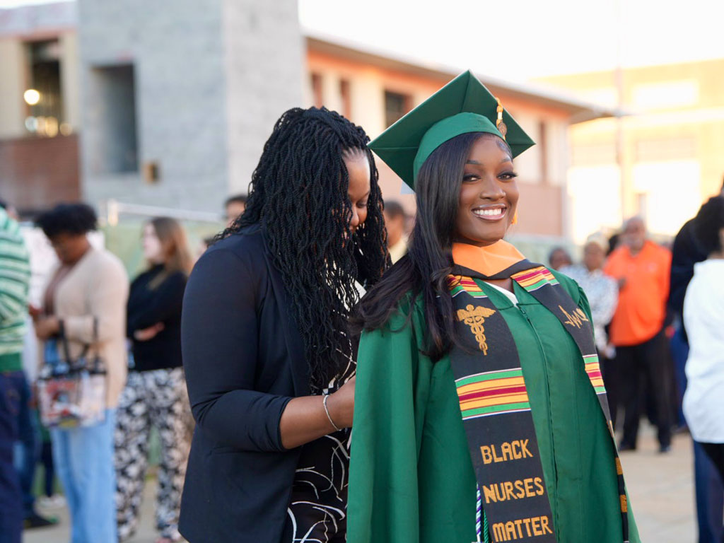 A mother and daughter at graduation, both in caps and gowns