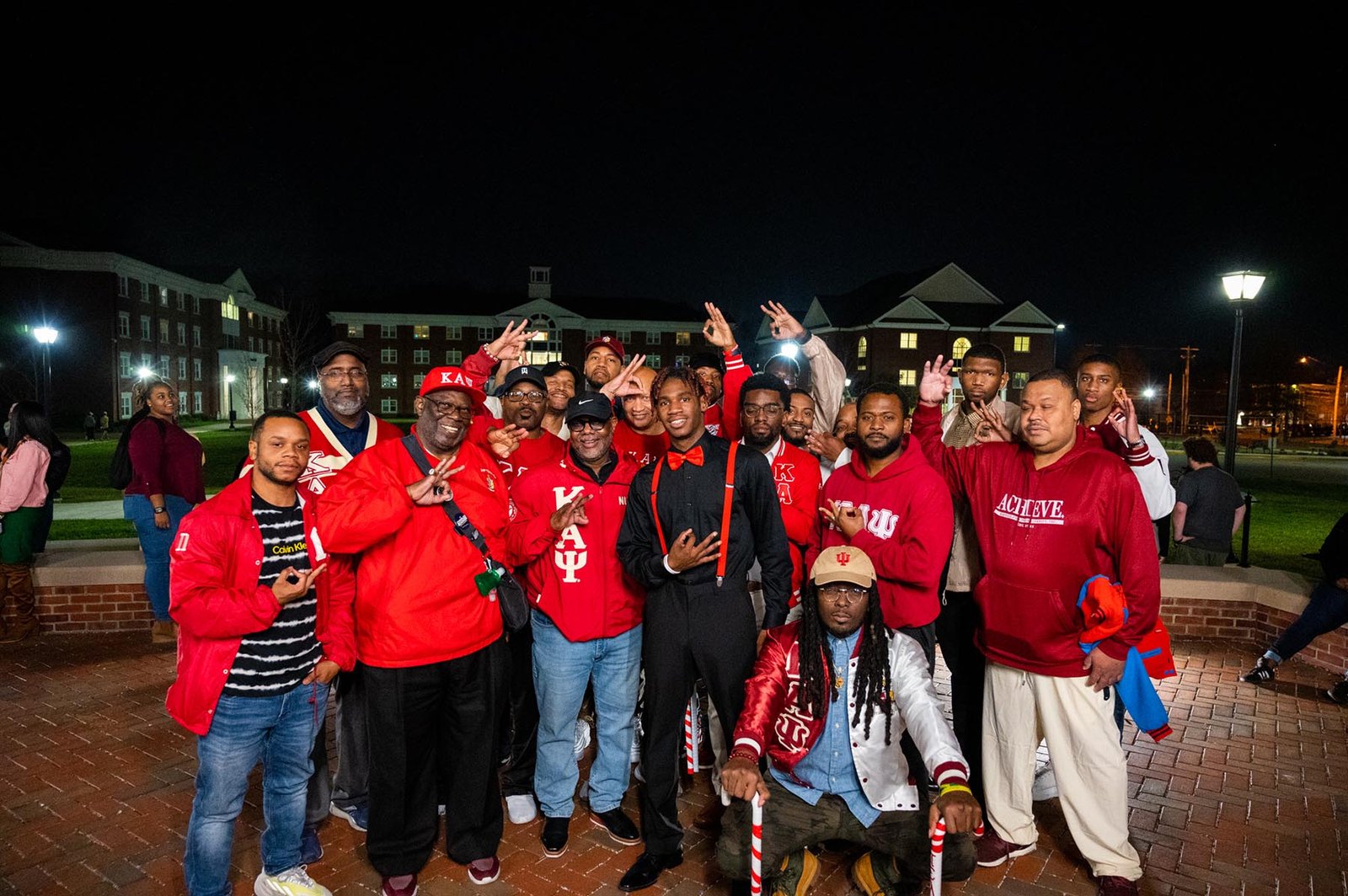 Kappa Alpha Psi members in letter jackets holding canes and giving the fraternity hand sign